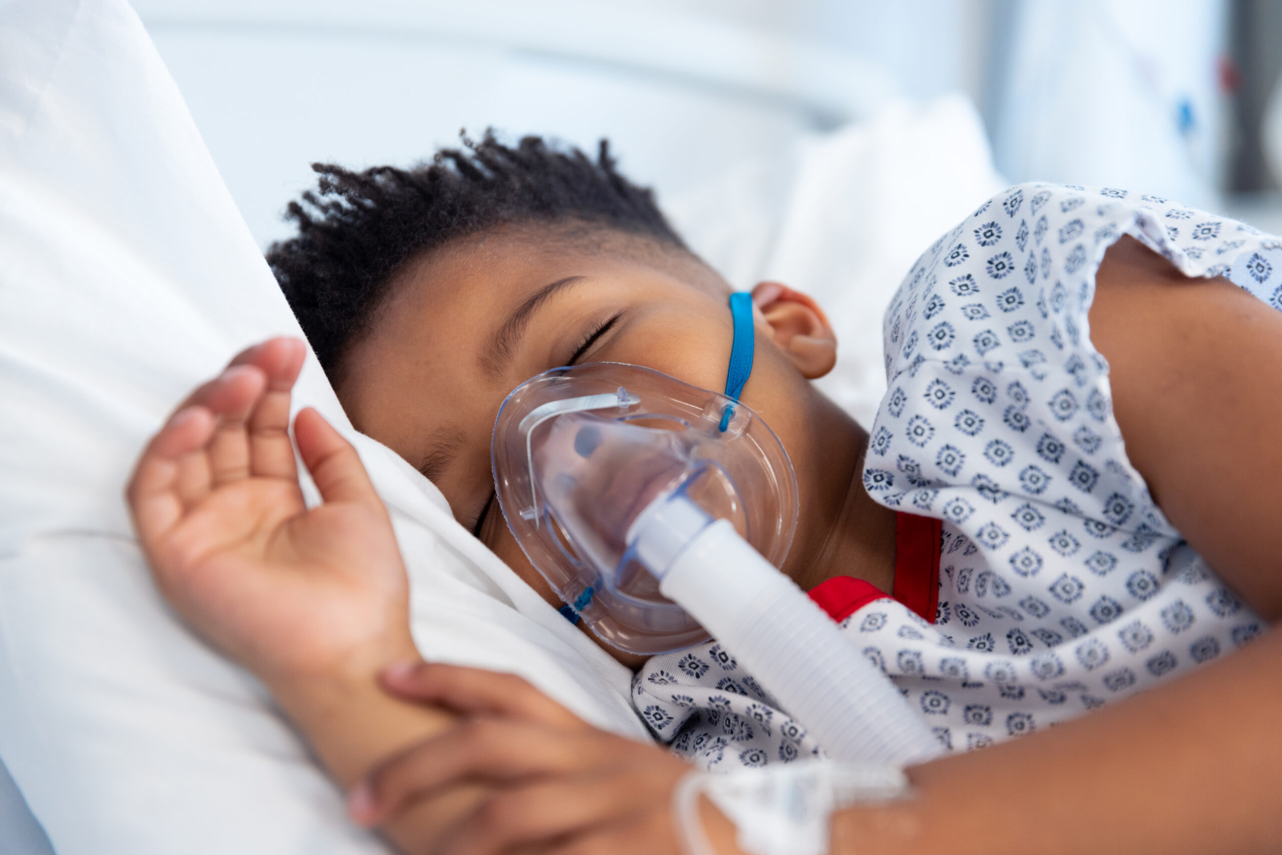 African american boy patient on ventilator asleep in hospital bed. Hospital, medical and healthcare services.
